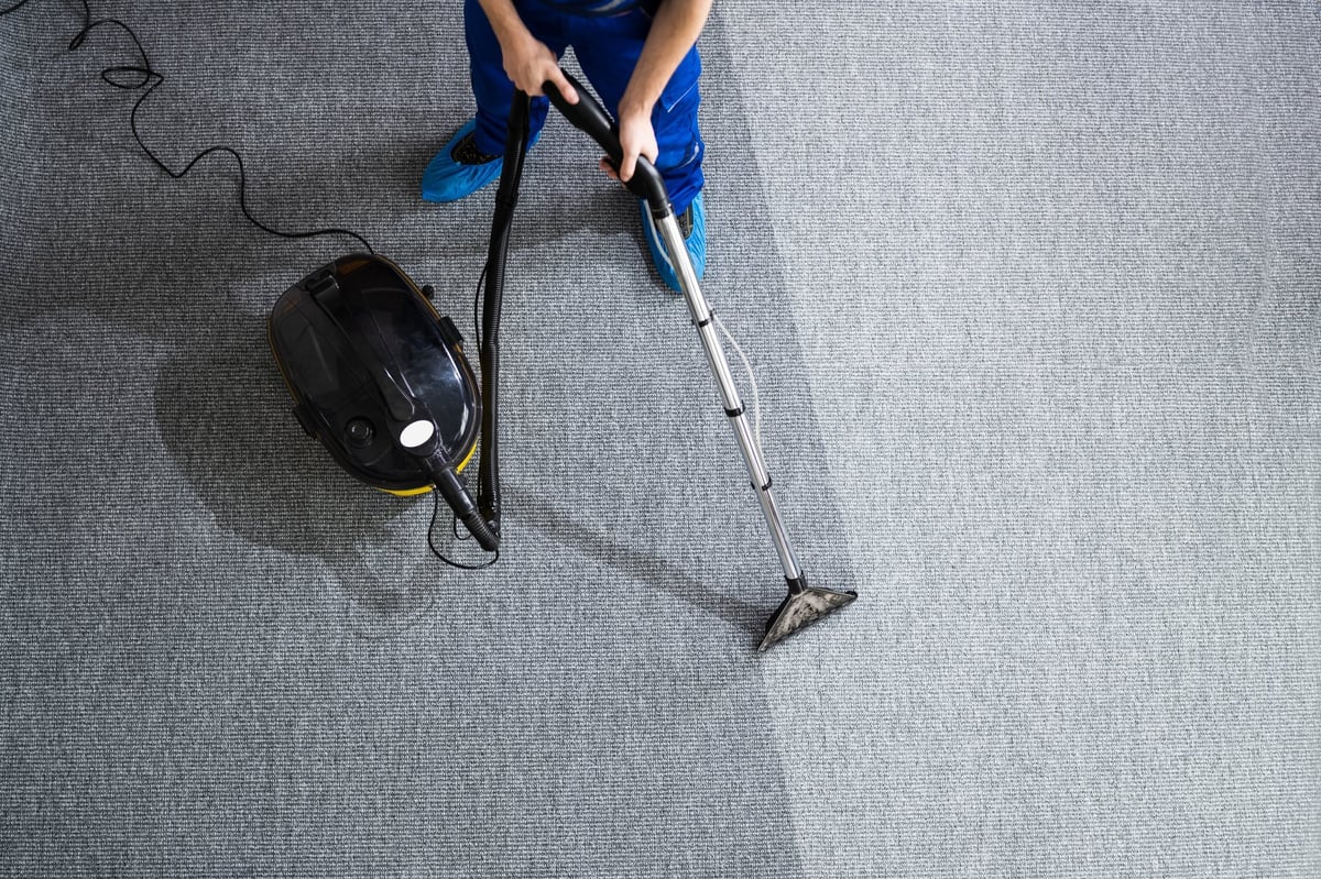Janitor cleaning carpet with a vacuum cleaner at home